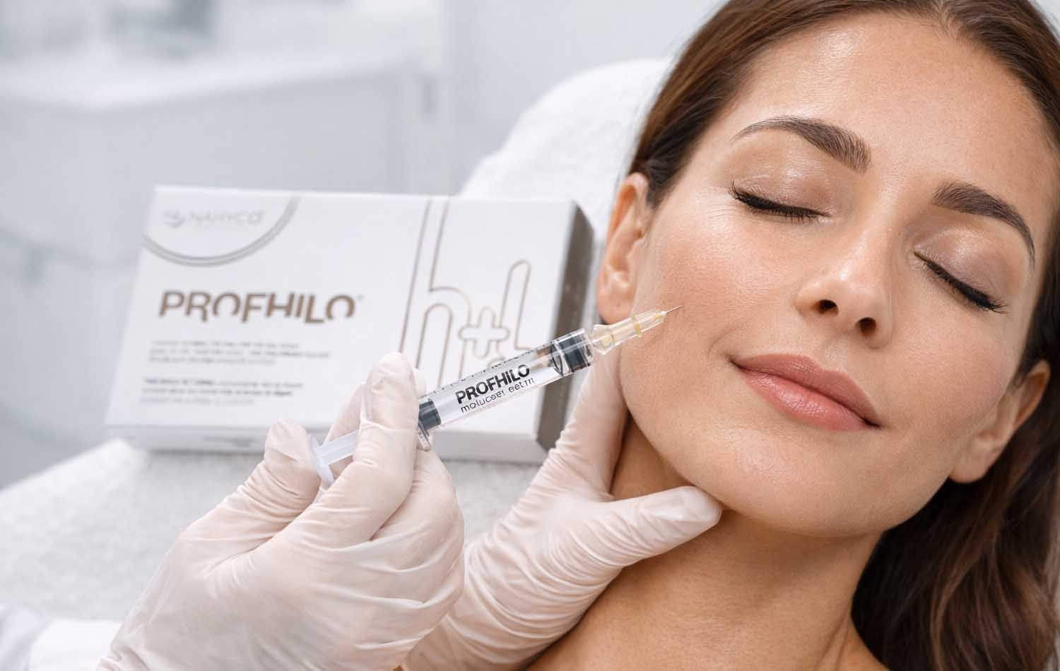 Provider injecting Profhilo into a client's cheek, with the Profhilo box visible in the background