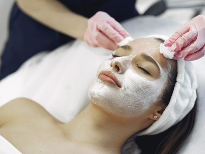 Esthetician removing a facial mask from a client's skin with cotton pads