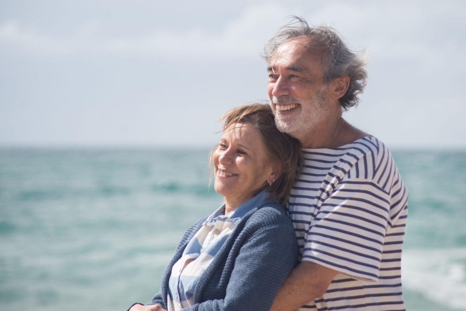 Smiling older couple embracing by the ocean