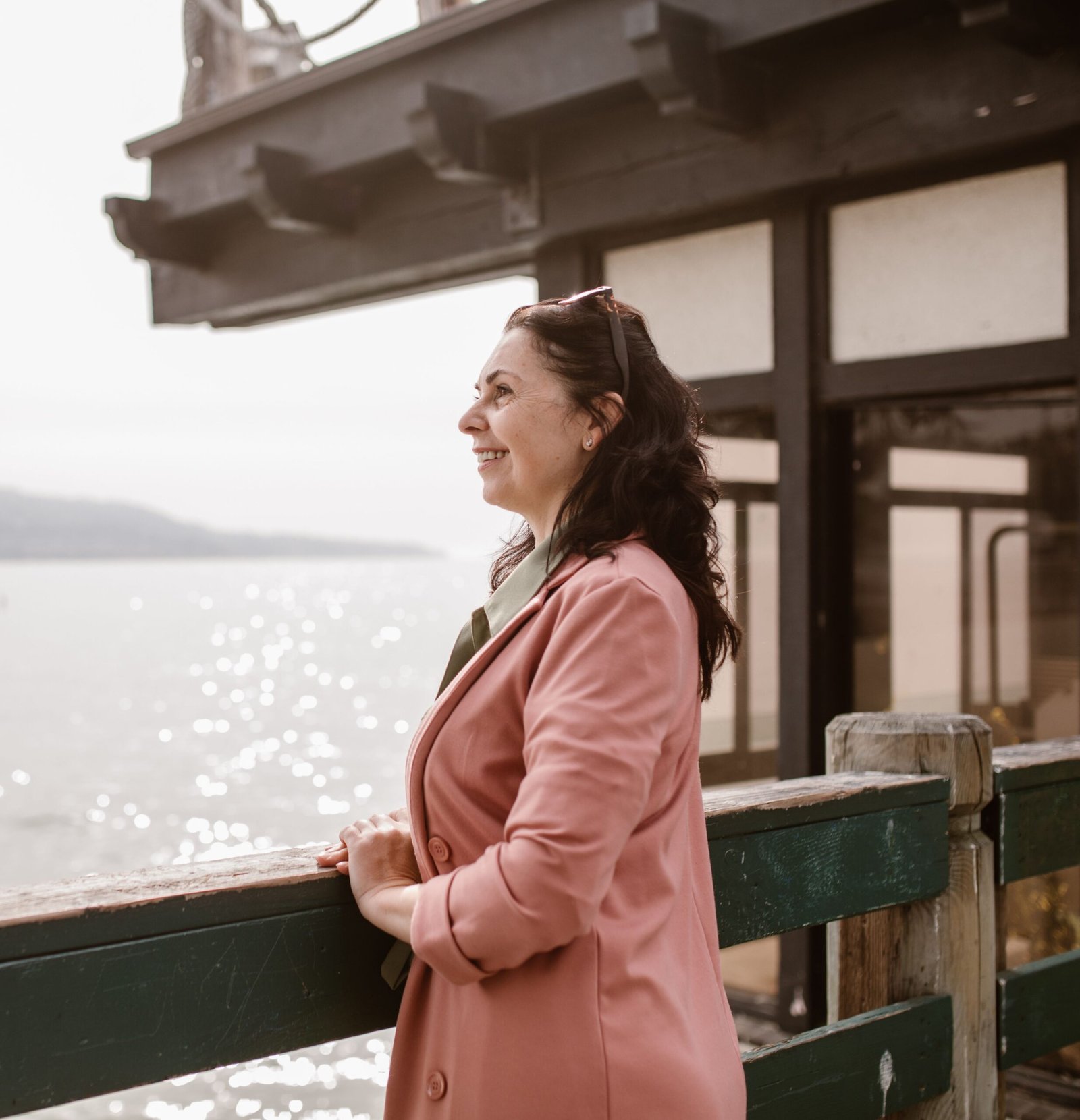 Smiling middle-aged woman in a pink coat looking out over the water