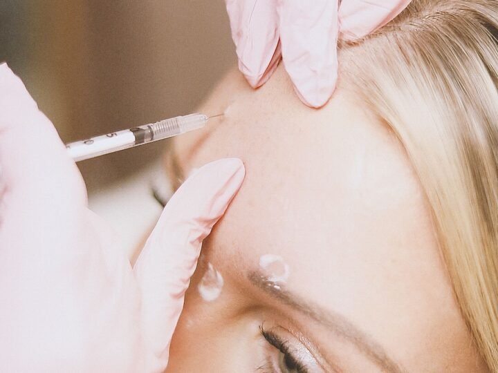 Provider in gloves injecting a forehead wrinkle treatment on a client
