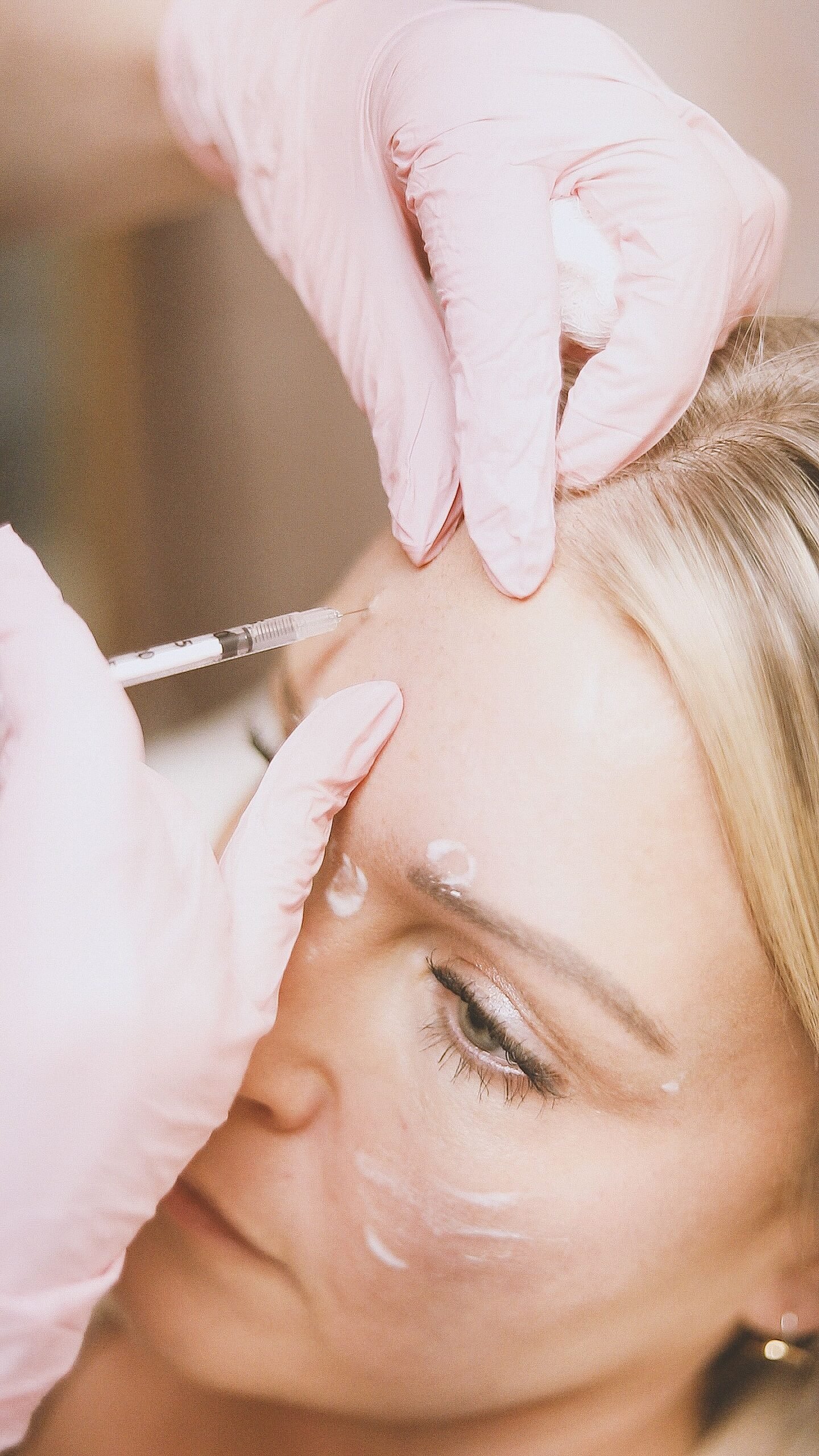 Provider in gloves injecting a forehead wrinkle treatment on a client