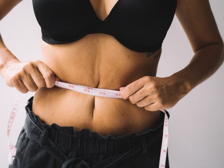 Woman in black activewear measuring her waist with a tape measure