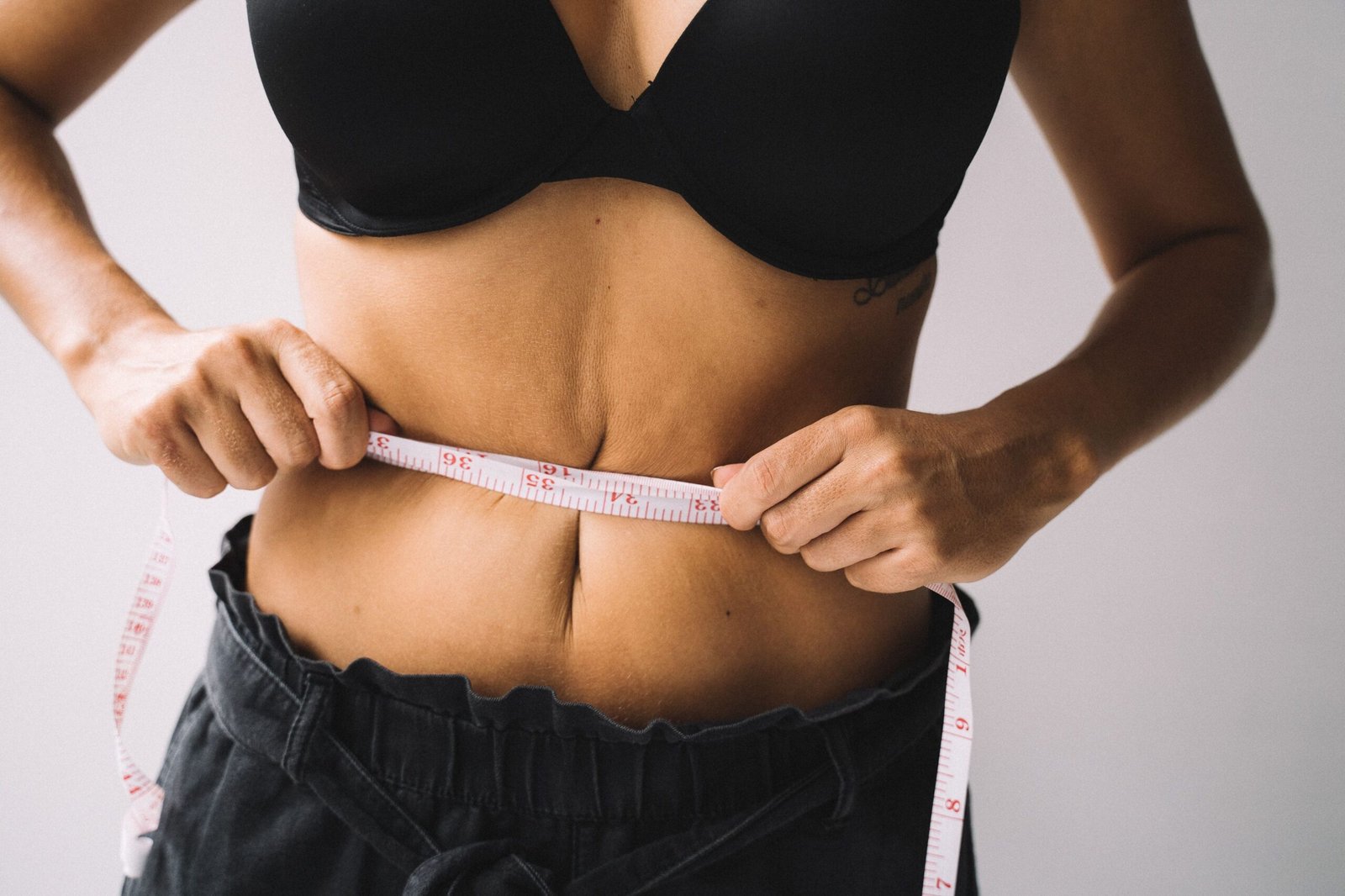 Woman in black activewear measuring her waist with a tape measure